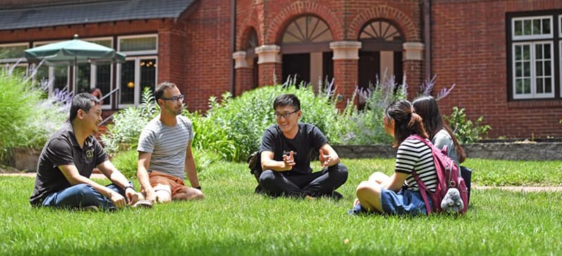 a small group of students sittin in the grass on the WashU campus