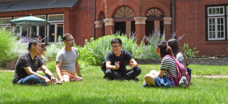 a small group of students sittin in the grass on the WashU campus